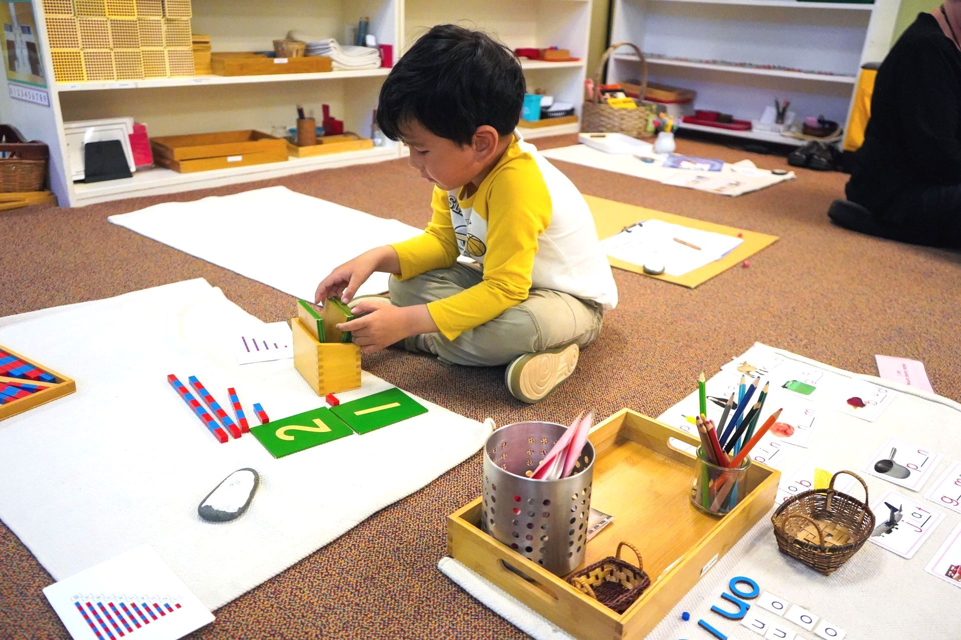 One Kindergarten Bridge student works on math skills with the Red and Blue Number Rods.