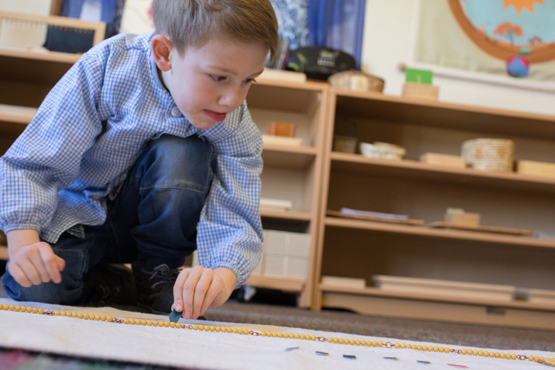 Kindergartener working on a Montessori math beads.