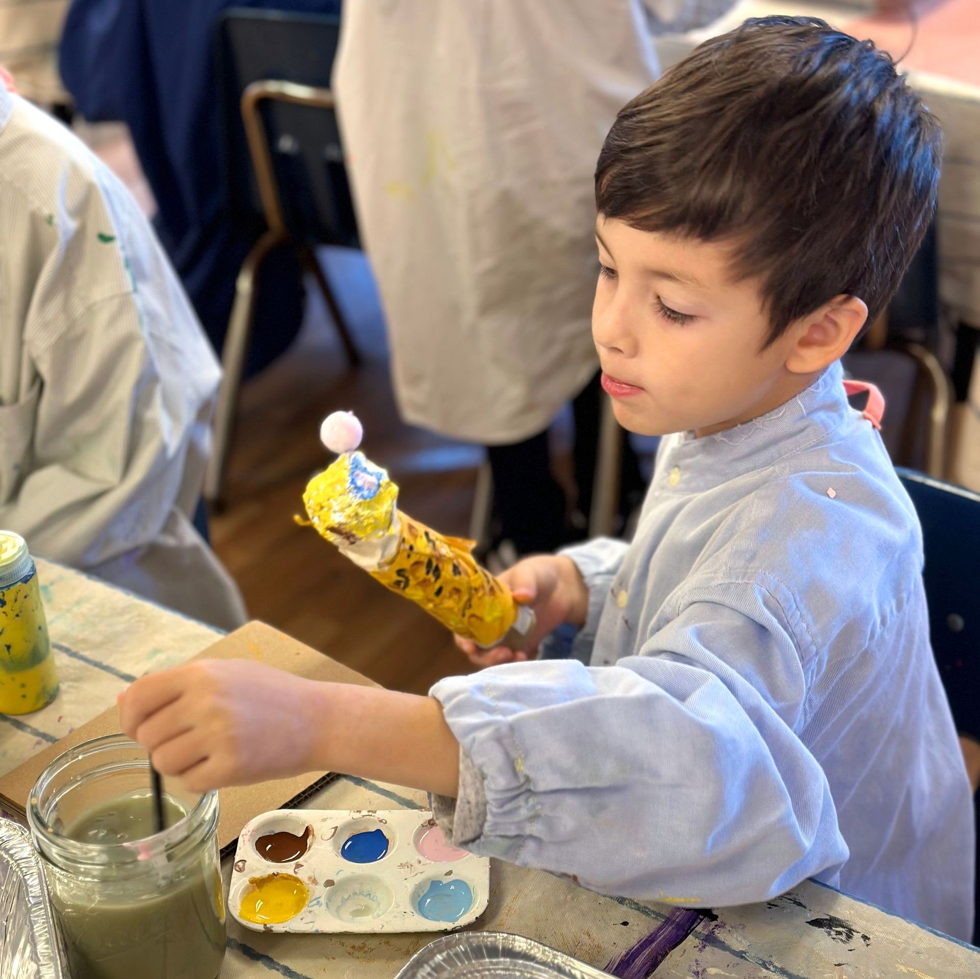 A Lower Elementary student paints his 3D sculpture of a leopard as part of his animal research report.