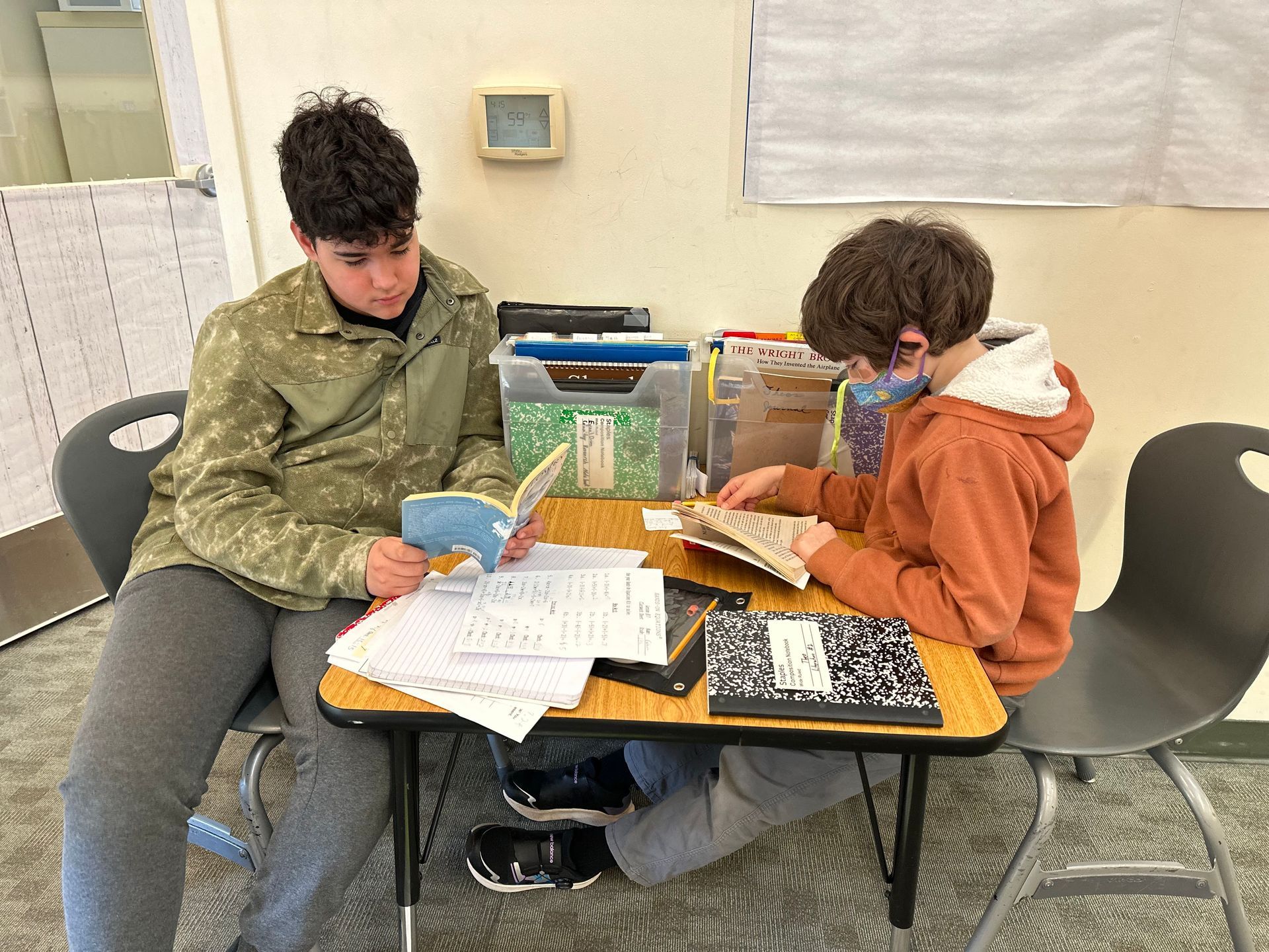 Two Upper Elementary students sitting together reading a book quietly.