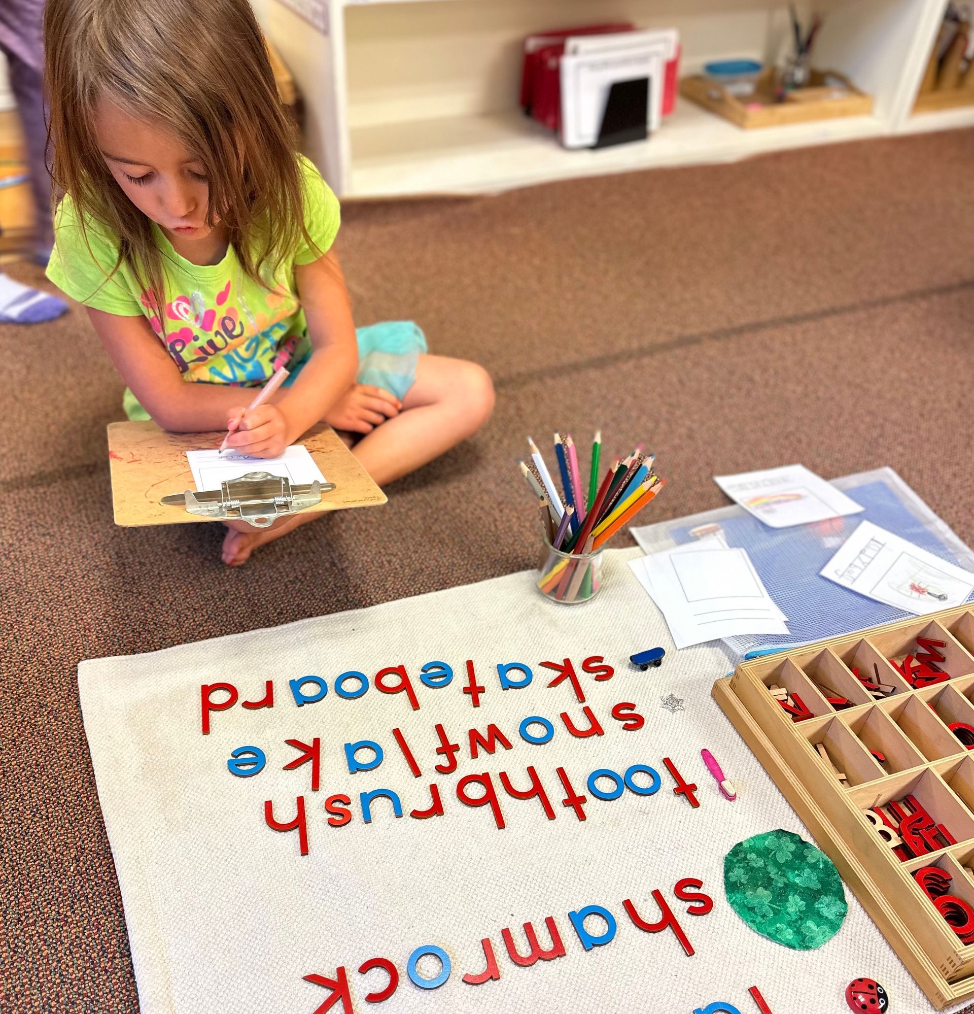 Kindergarten Bridge student practicing writing while working with the Montessori Moveable Alphabet.