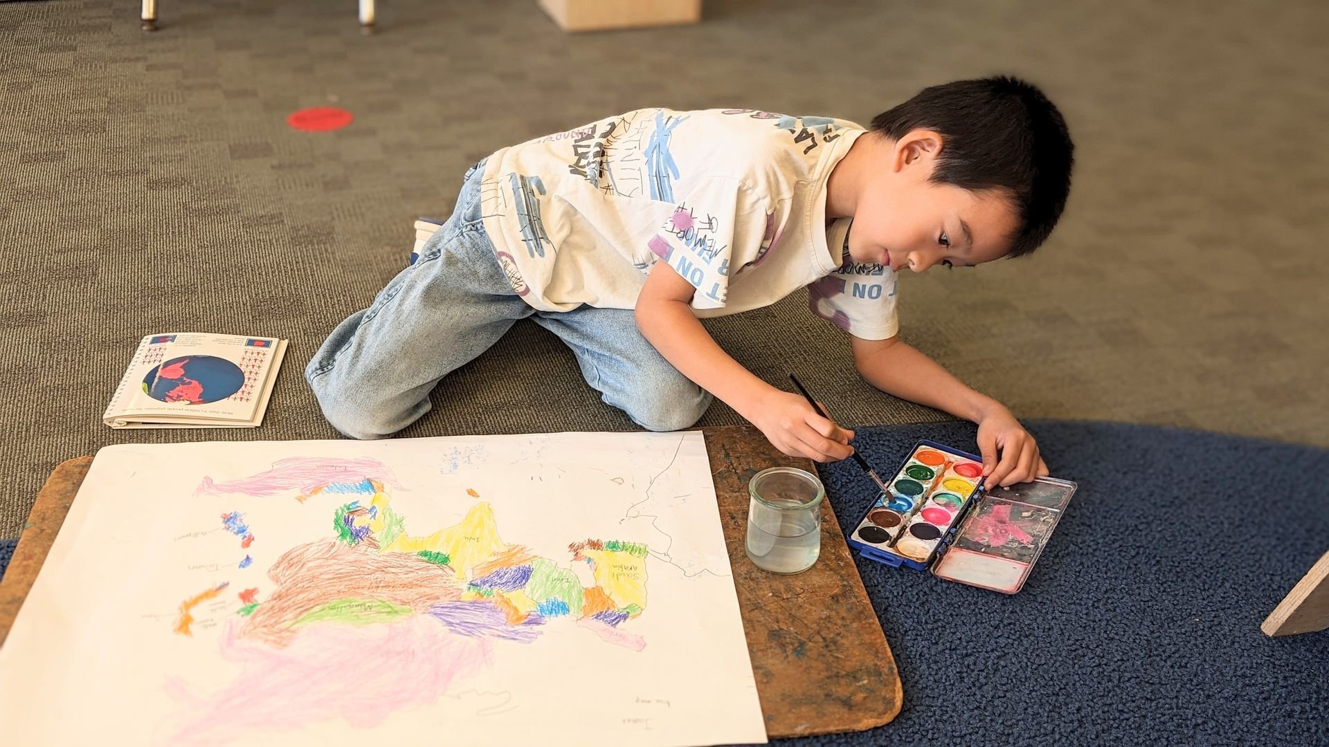 A Lower Elementary student painting his map of Asia with watercolors. Geography is a big part of the Montessori curriculum.