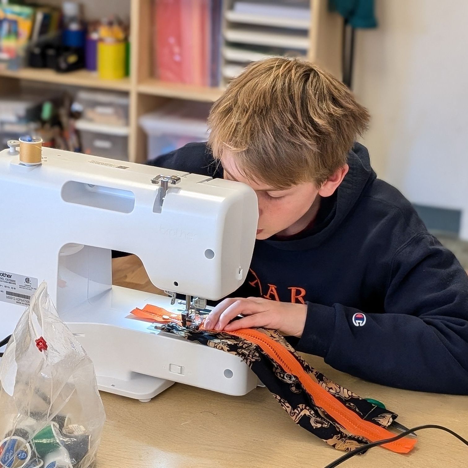 A 7th grader learns how to use a sewing machine in Art Class. Here he is sewing a zipper onto a pencil case he made all on his own.