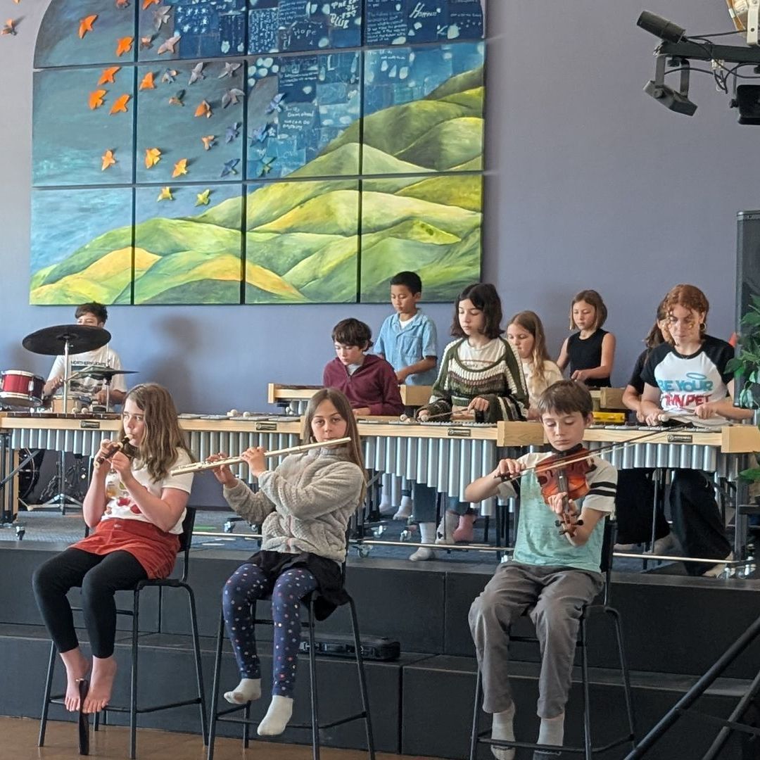 A group of Upper Elementary students practices on stage for the Spring Concert.