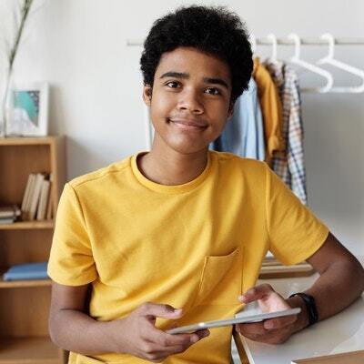 A Middle School student holding a notebook and smiling.