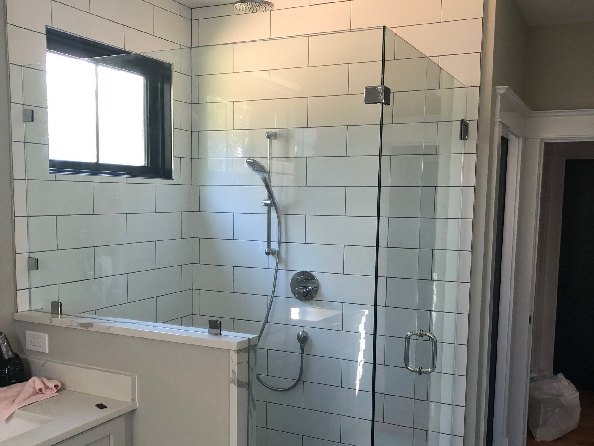 A bathroom with a walk in shower and a window