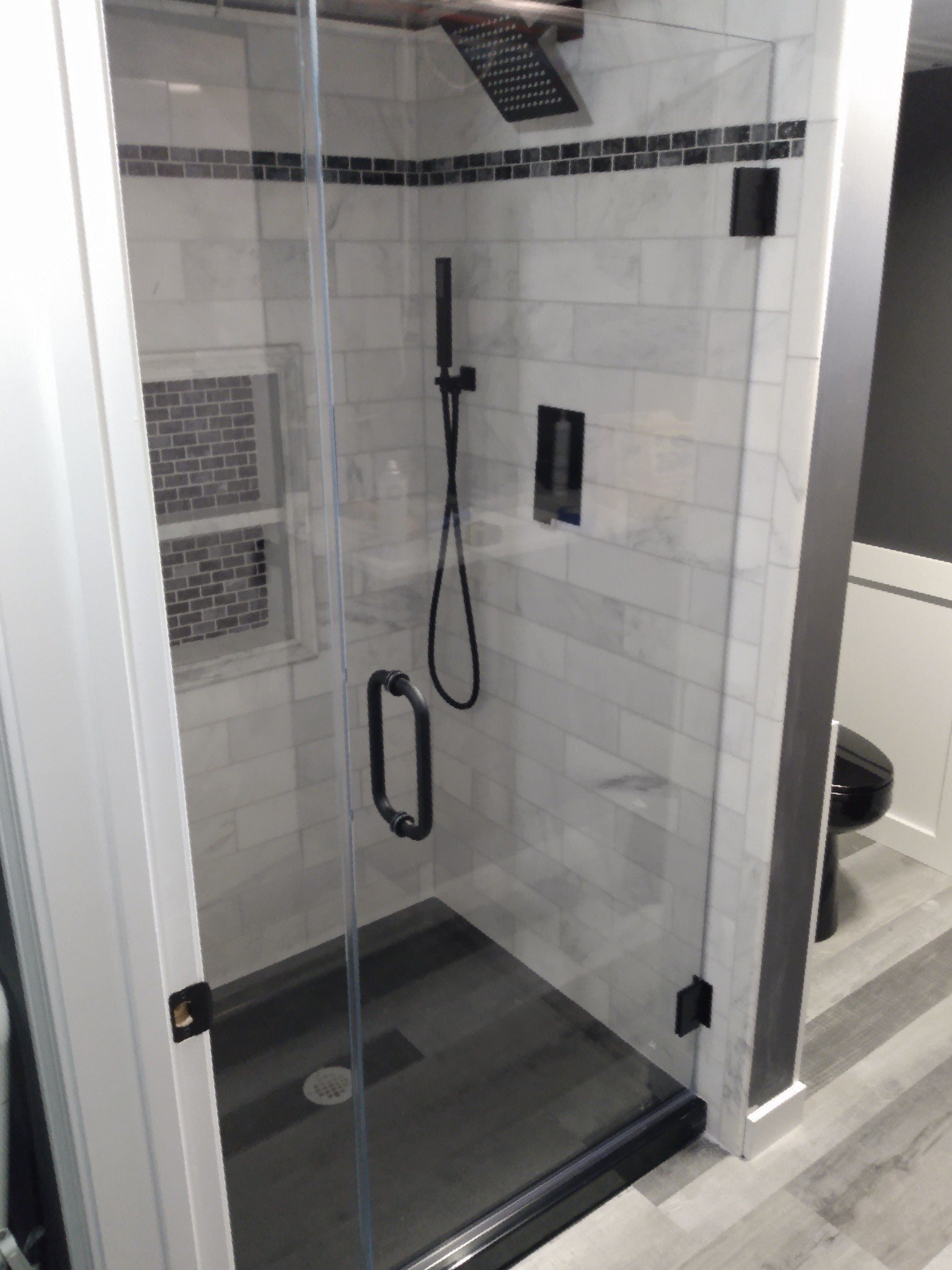 A bathroom with a walk in shower with a glass door.