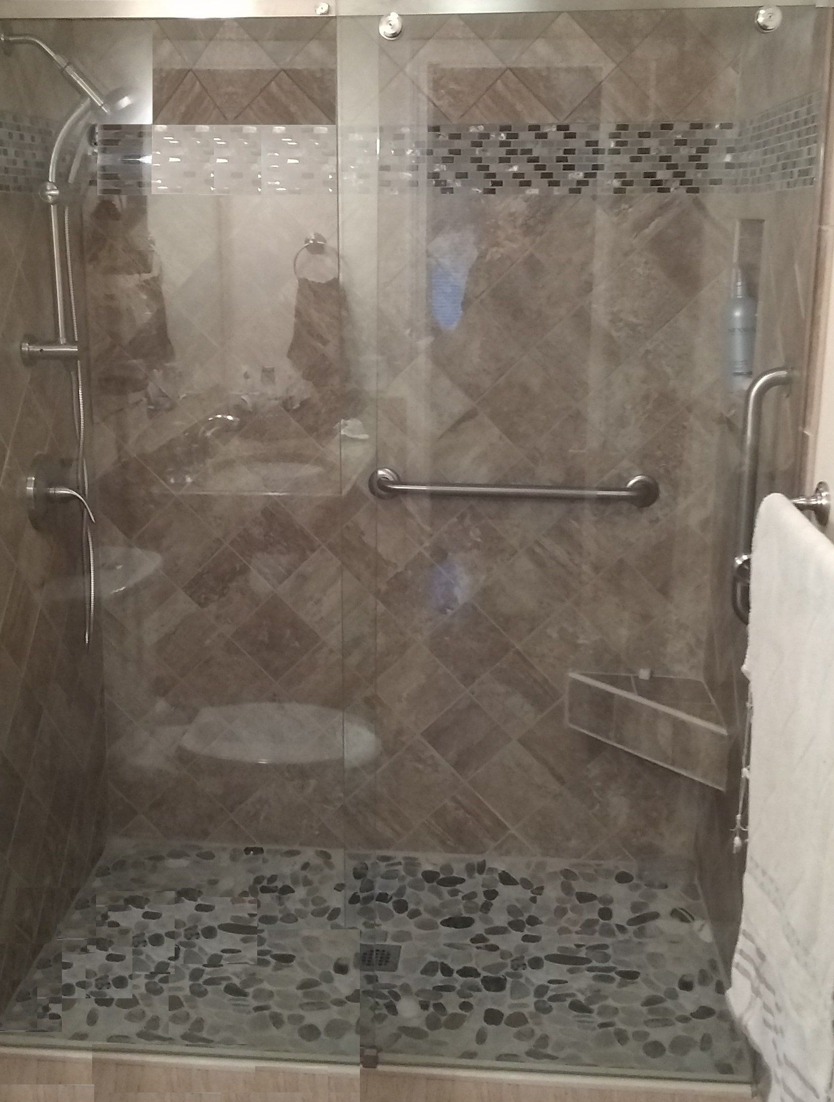 A bathroom with a walk in shower with a glass door.