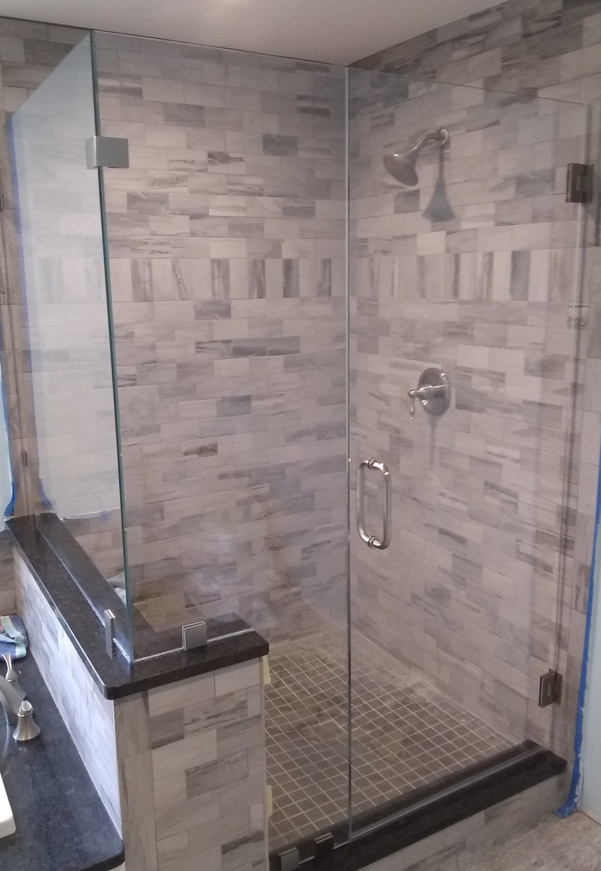 A bathroom with a walk in shower with a glass door.