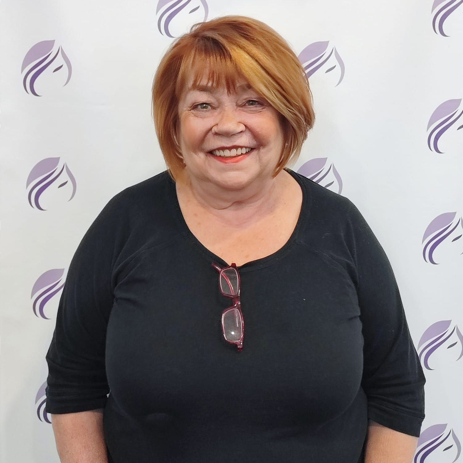 Eine Frau mit Brille und schwarzem Hemd lächelt in die Kamera