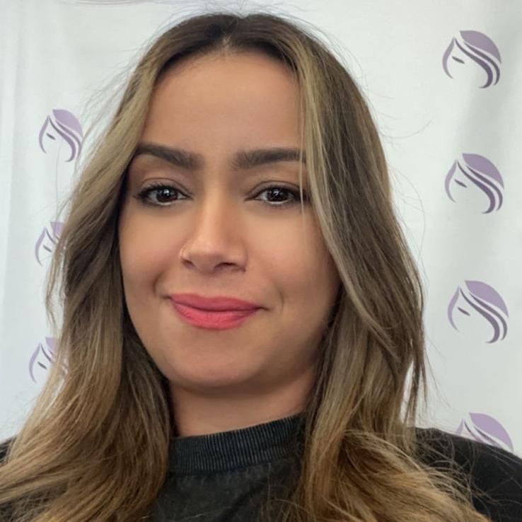 Eine Frau mit langen Haaren lächelt und trägt einen schwarzen Pullover.