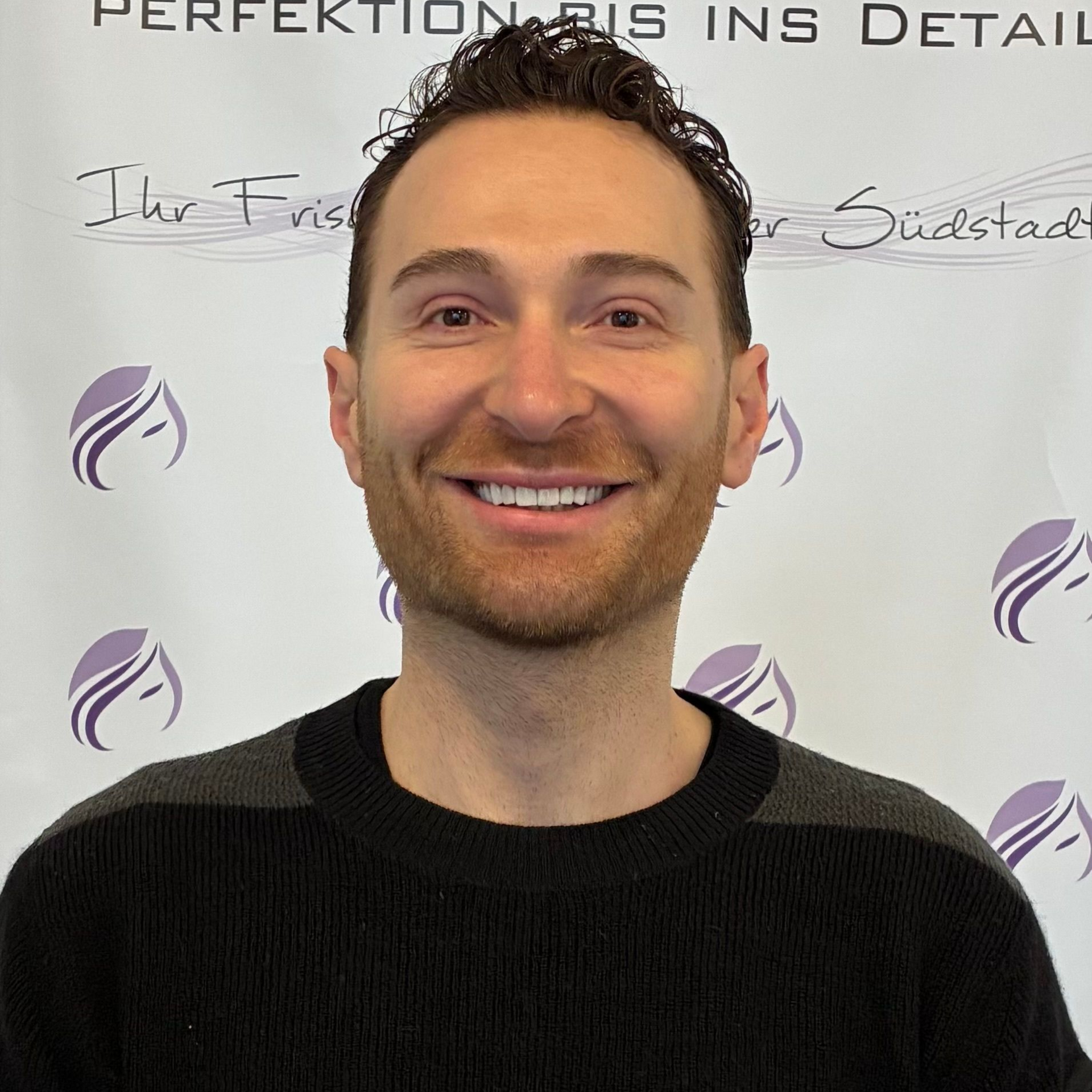 Eine Frau mit langen Haaren lächelt und trägt einen schwarzen Pullover.