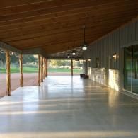 Empty covered patio with wood ceiling, polished concrete floor, and glass doors overlooking a yard