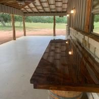 Rustic porch with a polished wooden table and open view of a grassy yard.