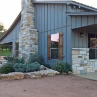 Modern house exterior with stone pillars, gray siding, and a landscaped entryway