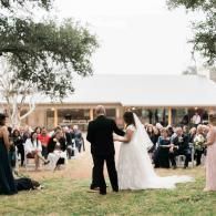 Bride and groom walk down the aisle at an outdoor wedding with seated guests on the lawn