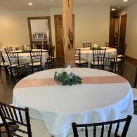 Elegant banquet room with round tables, white tablecloths, and black chairs