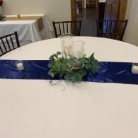 Round banquet table with blue runner and greenery centerpiece in a dining room