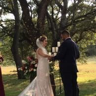 Bride and groom exchanging vows under trees at an outdoor wedding ceremony