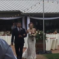 Bride and groom walking together at an outdoor wedding reception under a tent