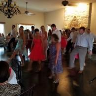 People dancing in a warmly lit room with a stone wall and dark wood floor