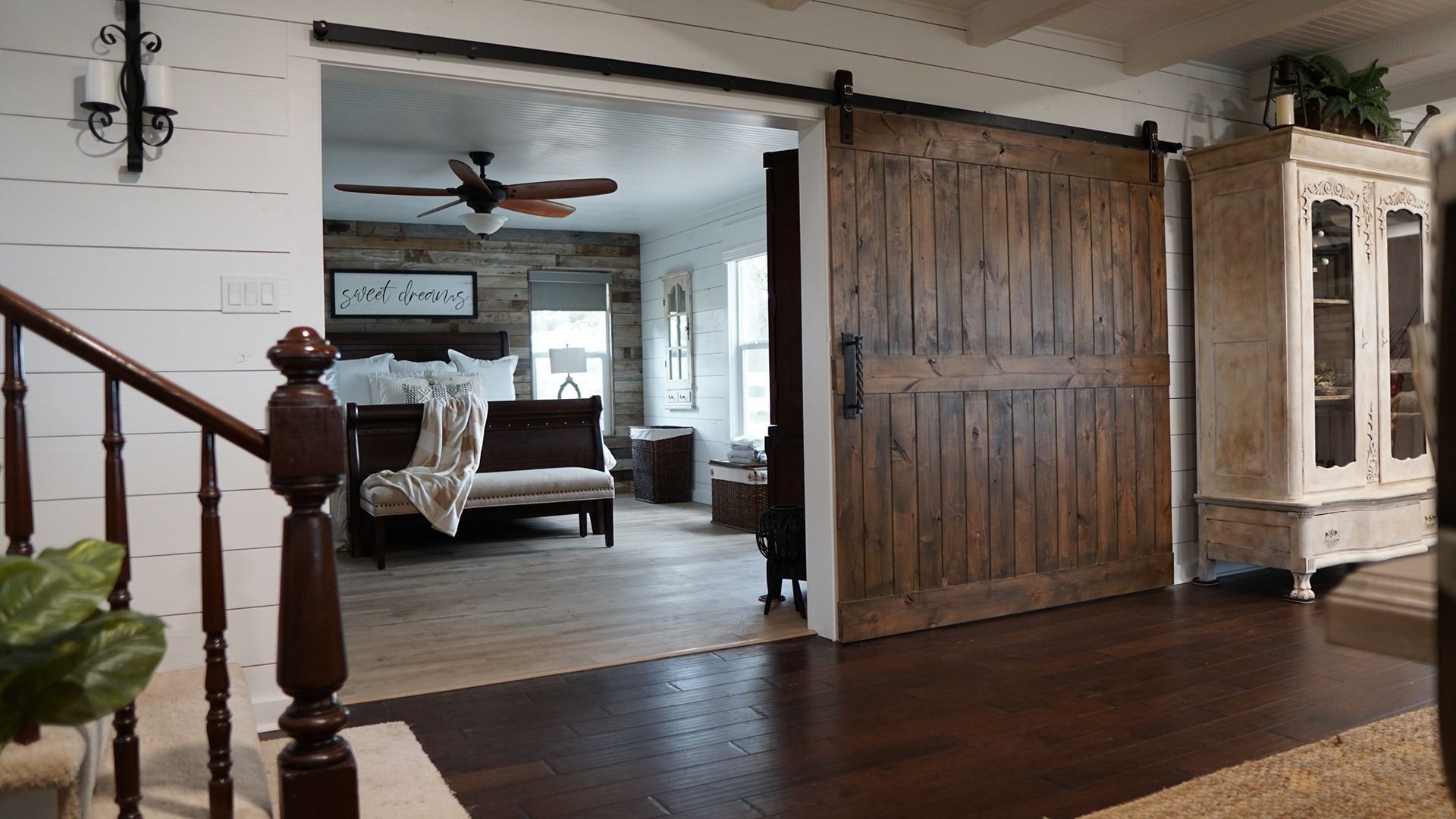 A living room with a sliding barn door leading to a bedroom.