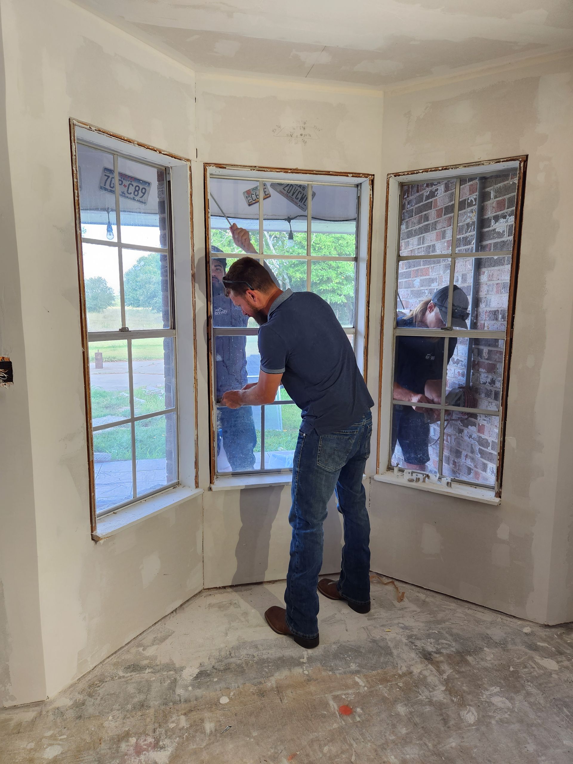 A man is installing a window in a corner of a room.