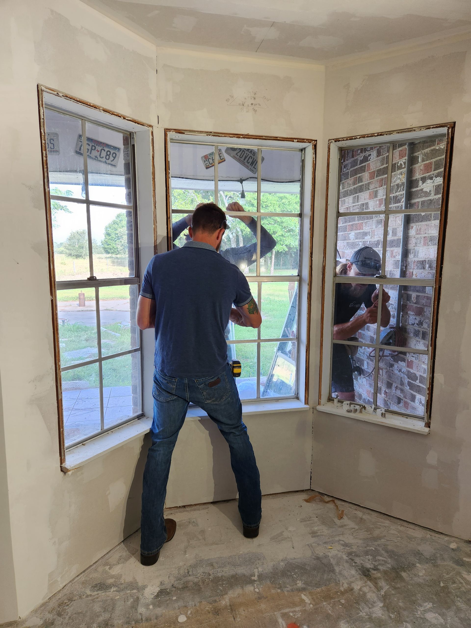 Two men are working on a window in a room.