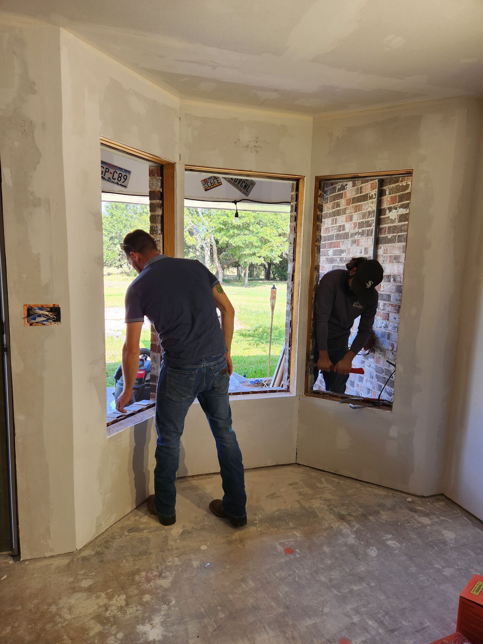 Two men are working on a window in a room.