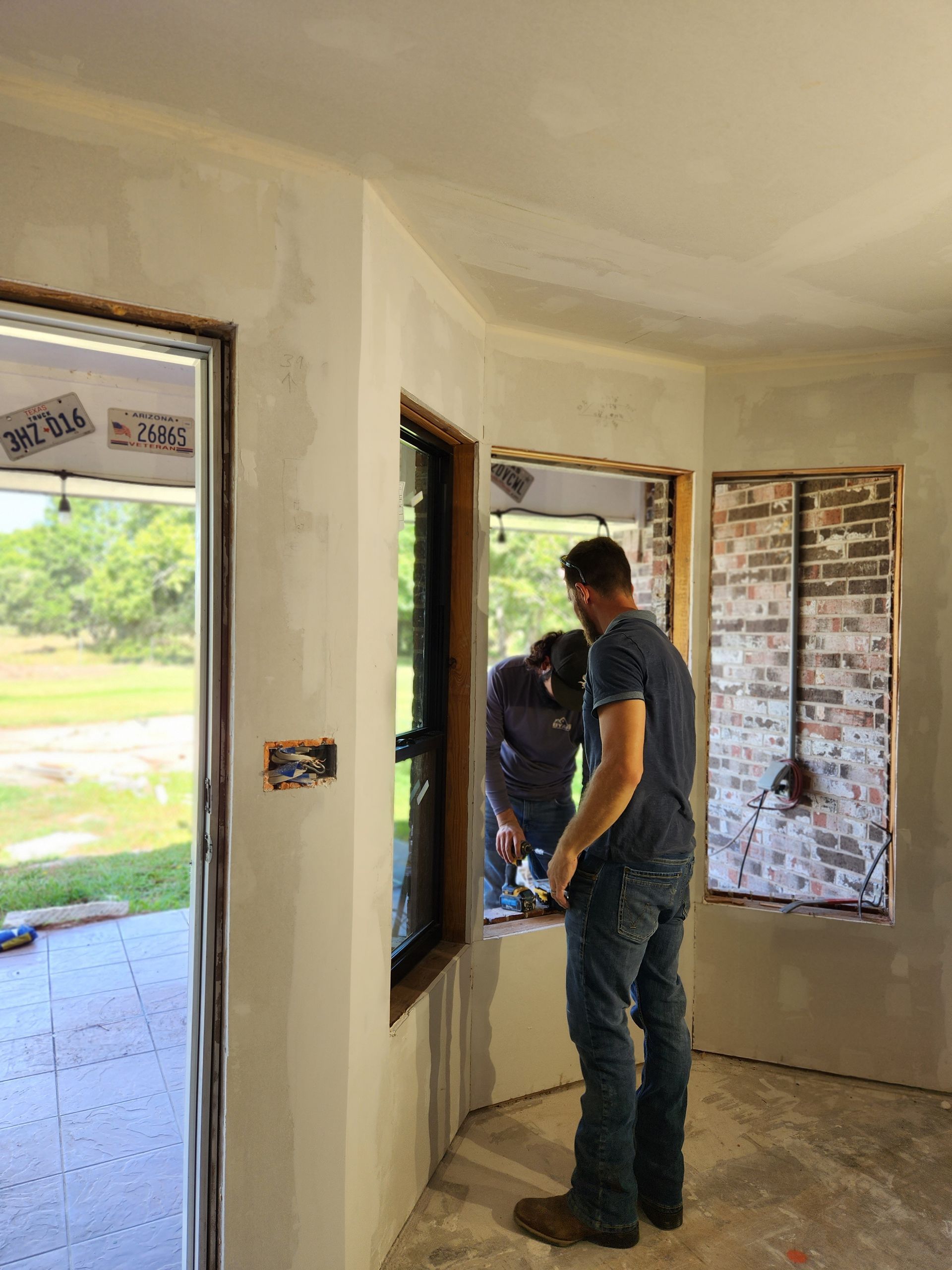 Two men are working on a window in a room.