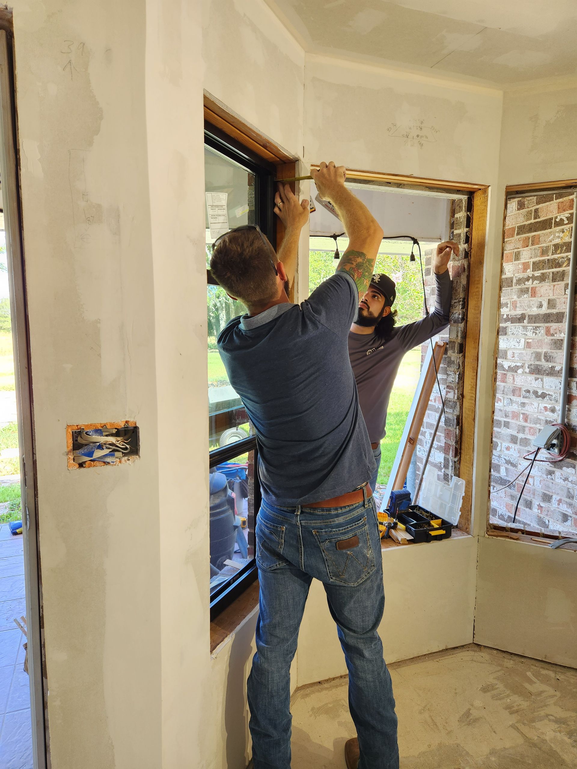 Two men are working on a window in a room.