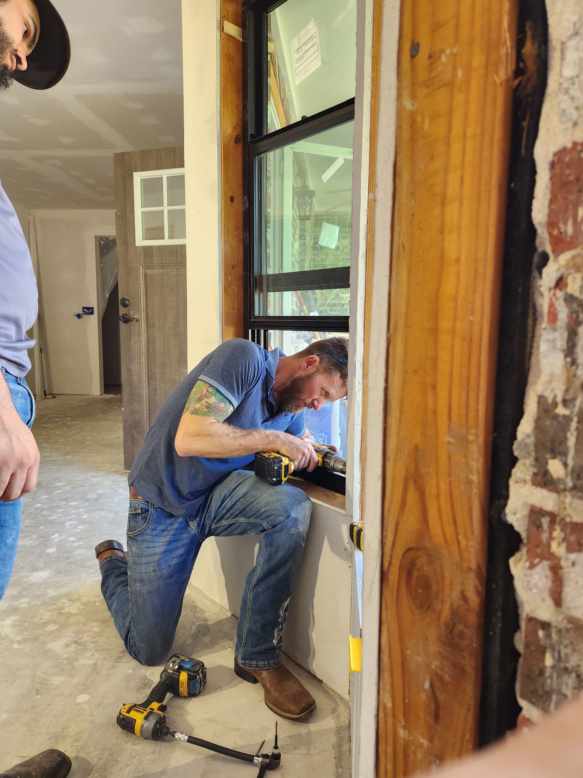 Two men are working on a window in a room.