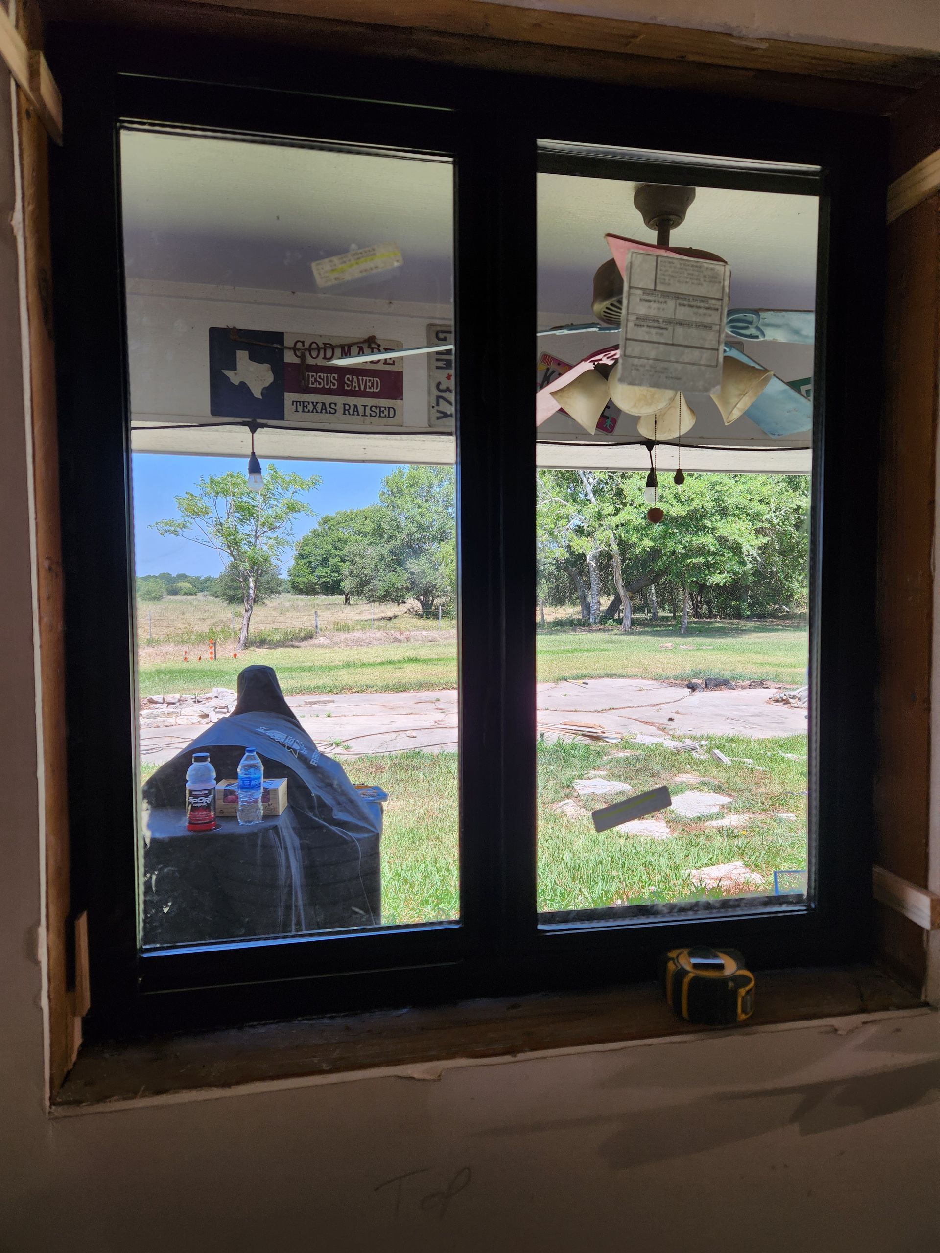 A window with a view of a field and a texas flag hanging from the ceiling.