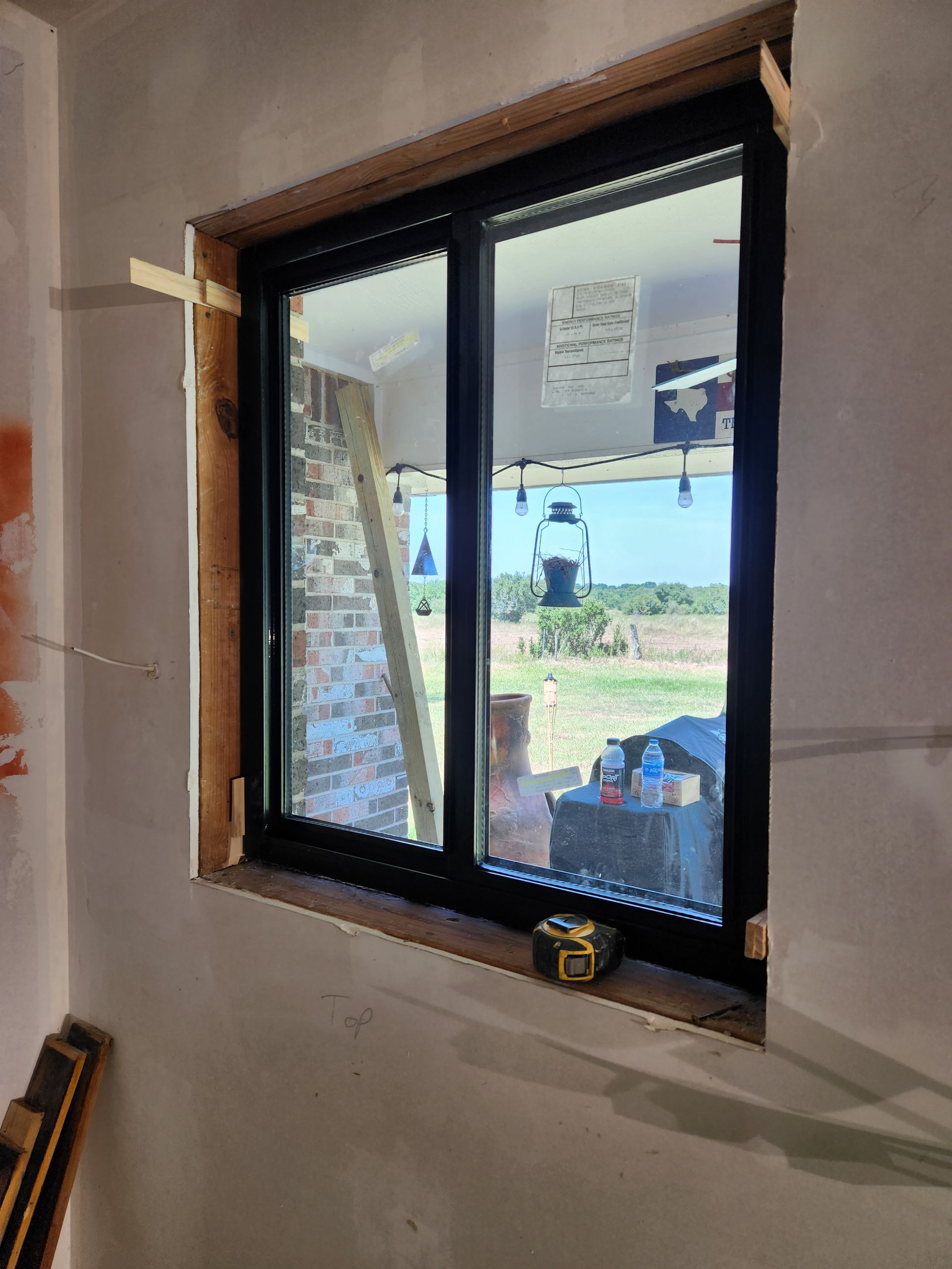 A window is being installed in a room with a tape measure on the window sill.