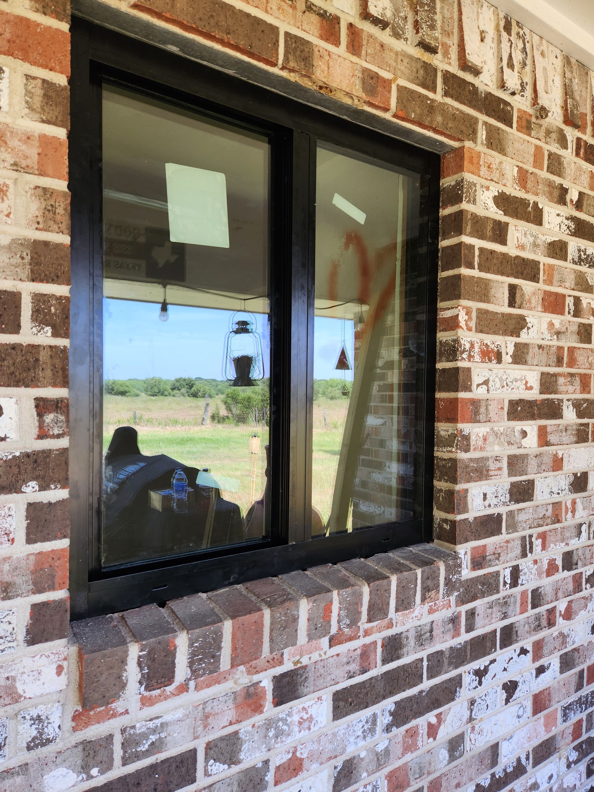 A brick wall with a black window on it.