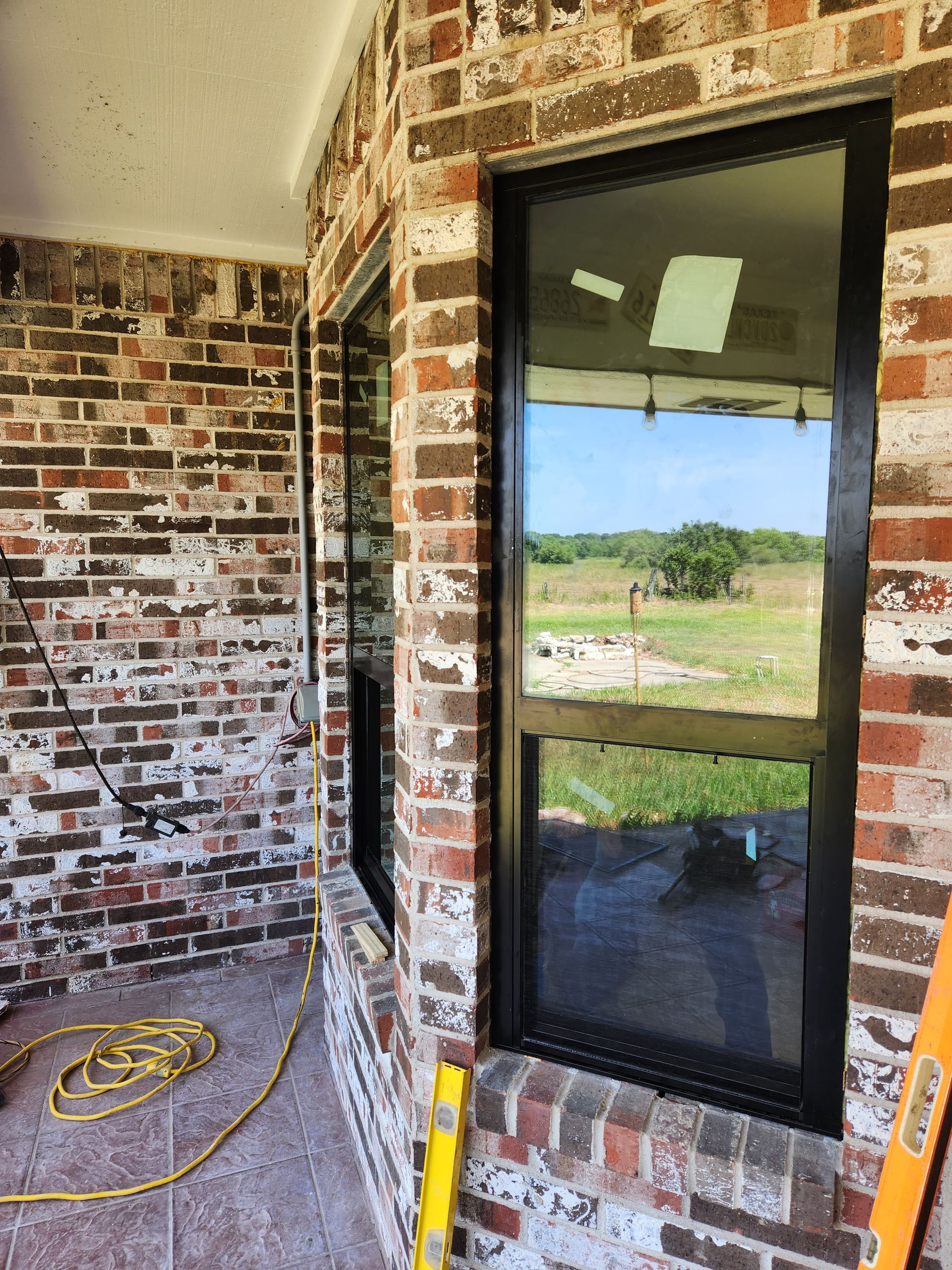 A brick building with two windows and a ladder on the side.