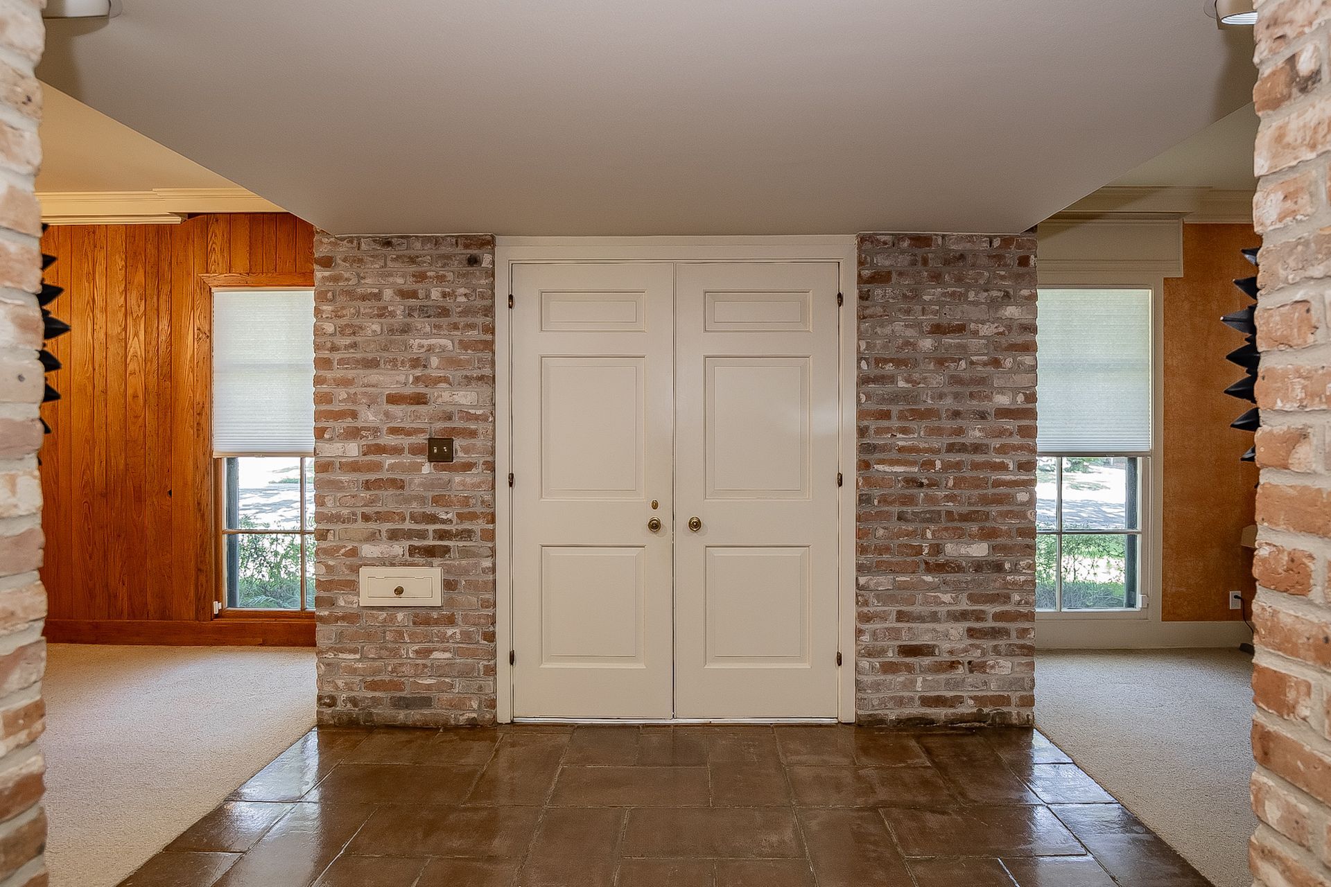 A hallway with a brick wall and white doors