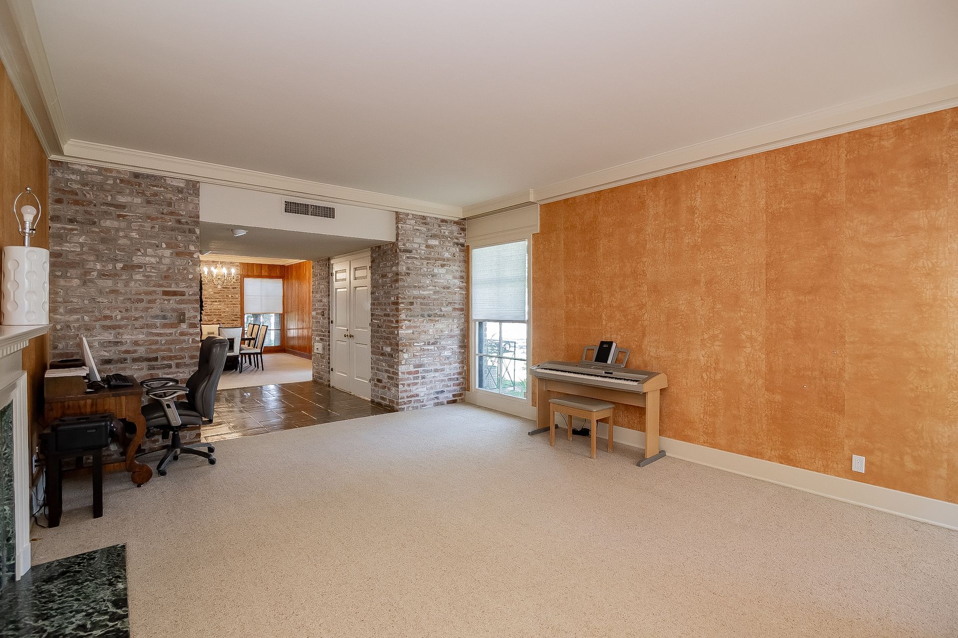 An empty living room with a piano and a fireplace.