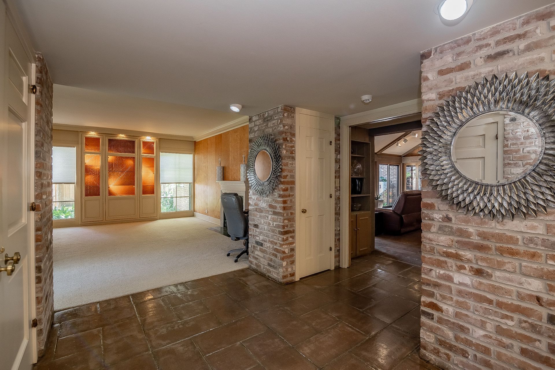 A hallway in a house with a brick wall and a mirror.
