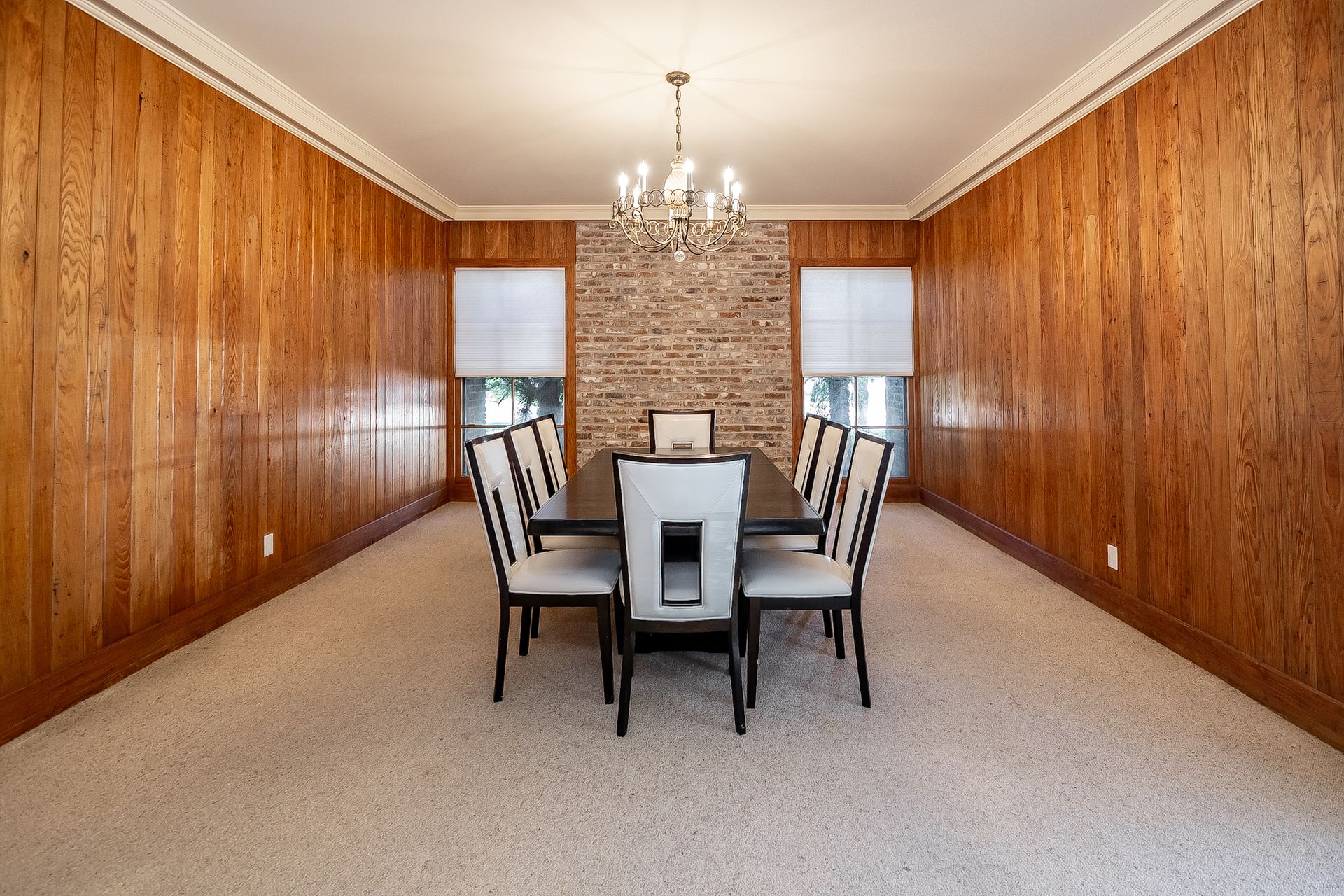 A large dining room with a long table and chairs and a chandelier.