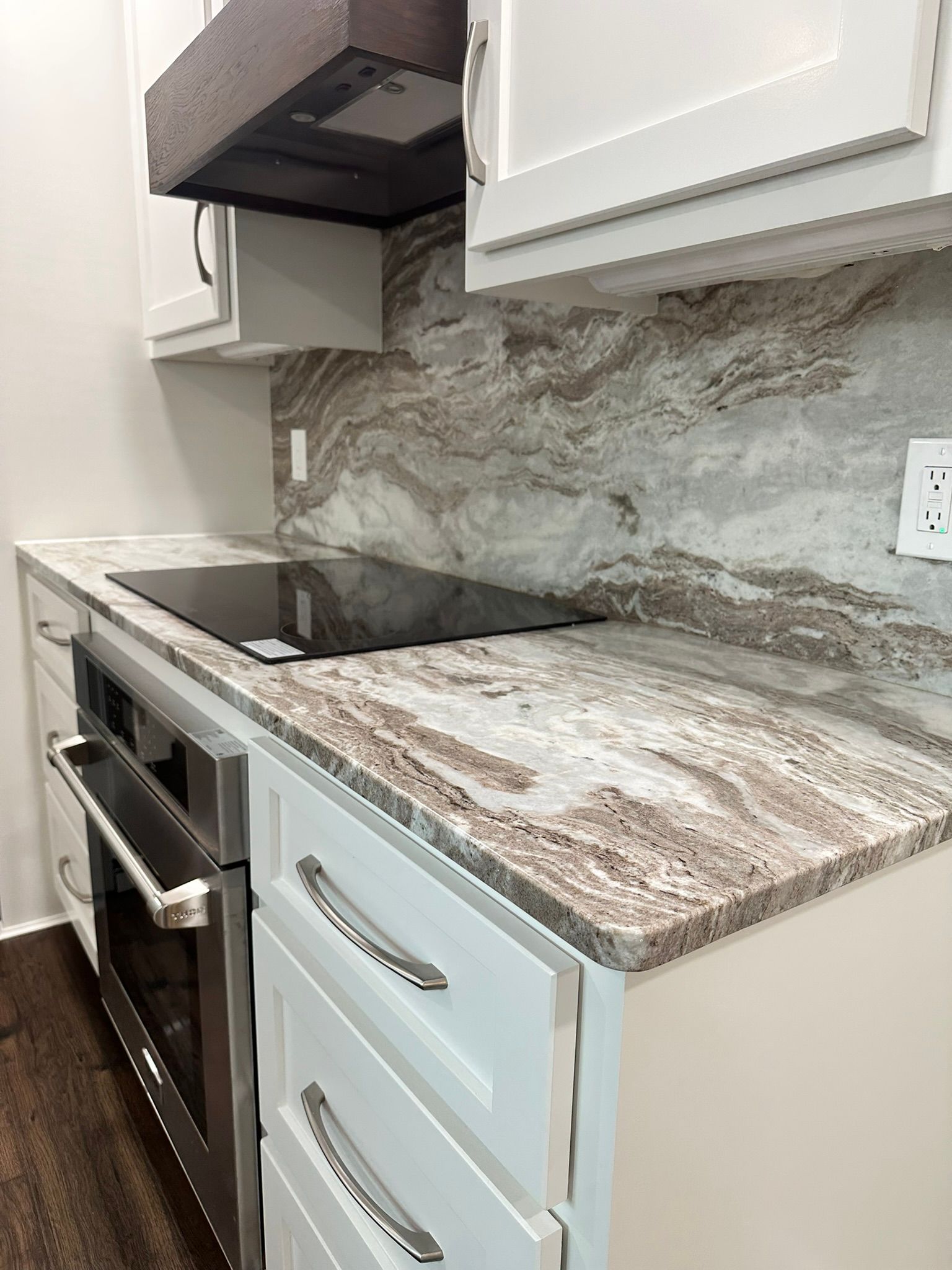 A kitchen with granite counter tops , stainless steel appliances , and white cabinets.