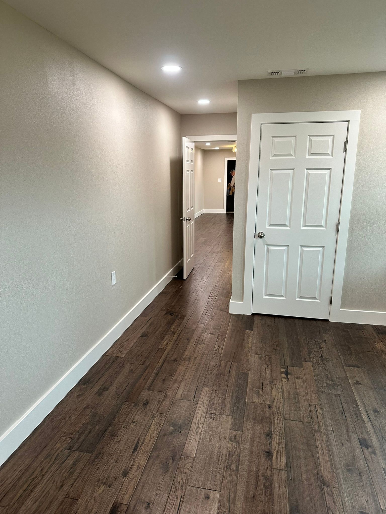 A hallway with hardwood floors and a door in a house.
