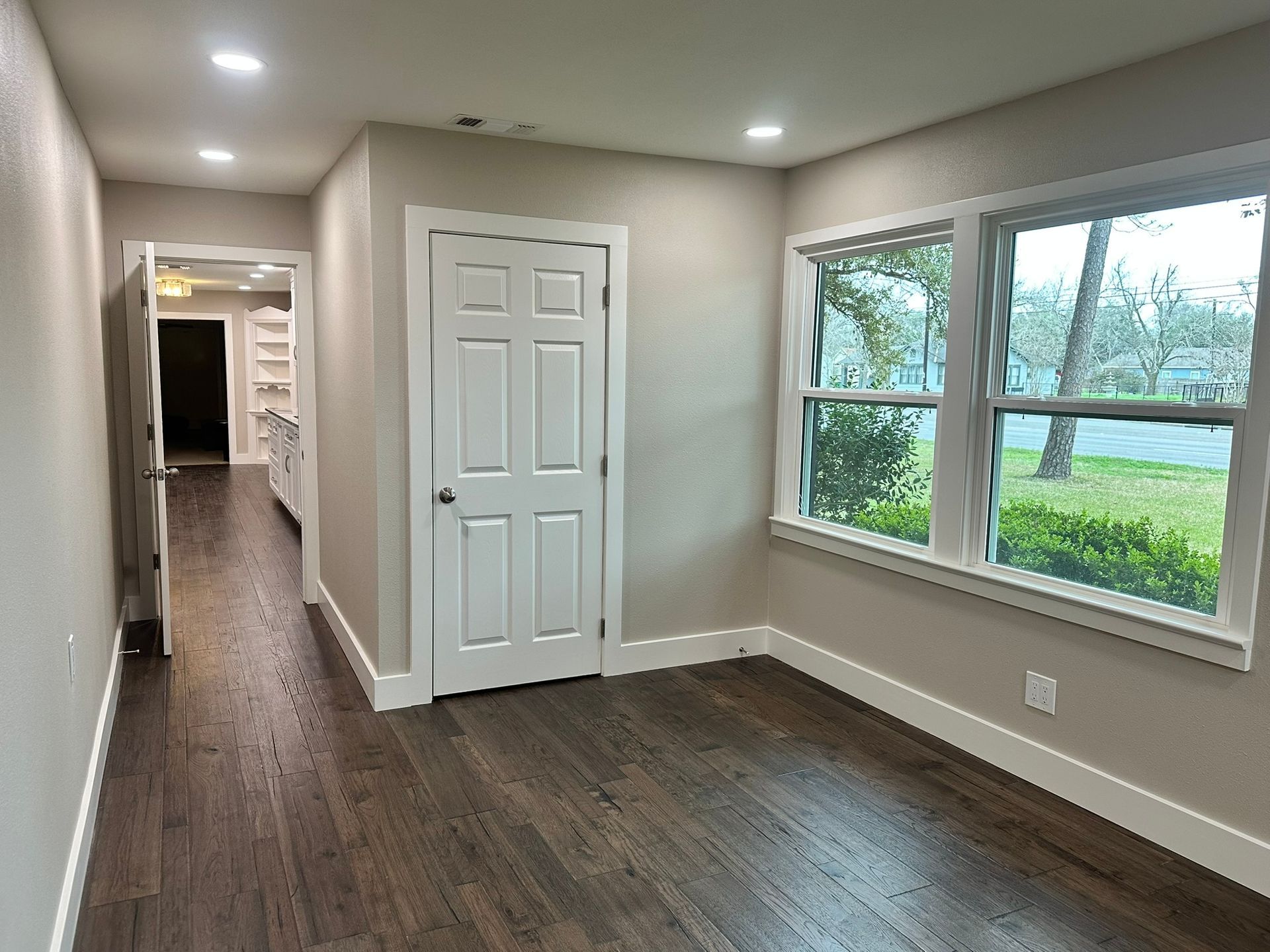 An empty room with hardwood floors and two windows.