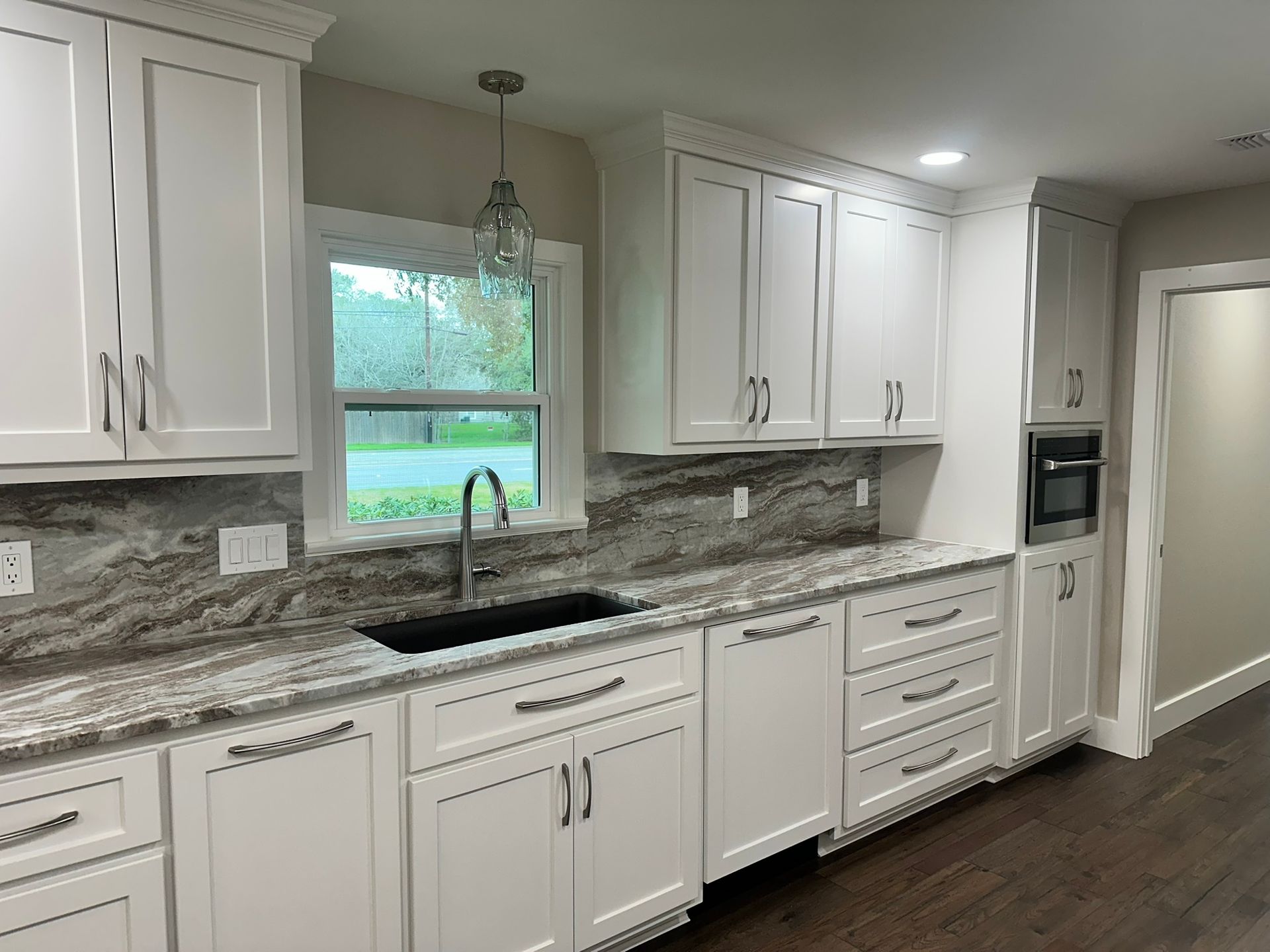 A kitchen with white cabinets and granite counter tops.
