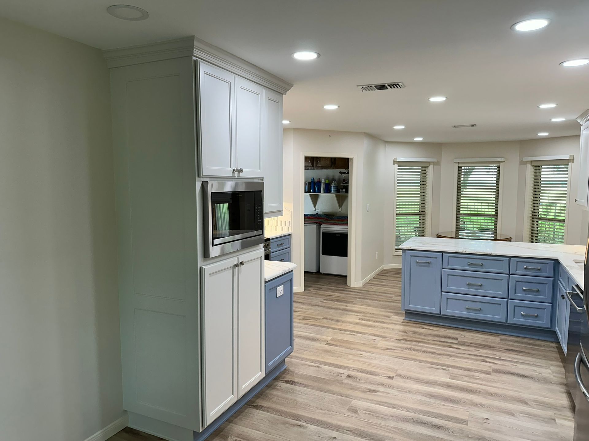 A kitchen with blue cabinets , white cabinets , and stainless steel appliances.