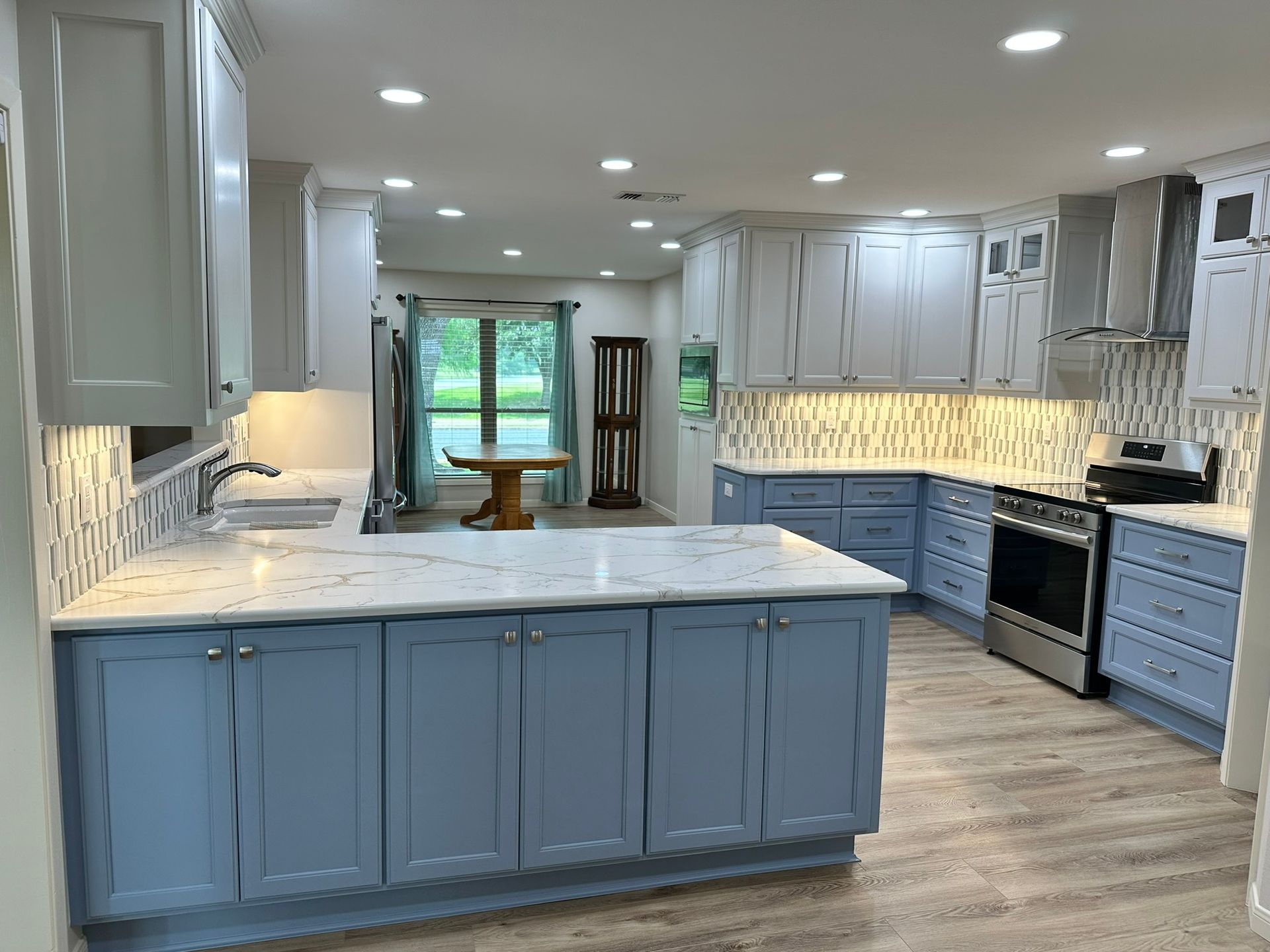 A kitchen with blue cabinets and white counter tops.