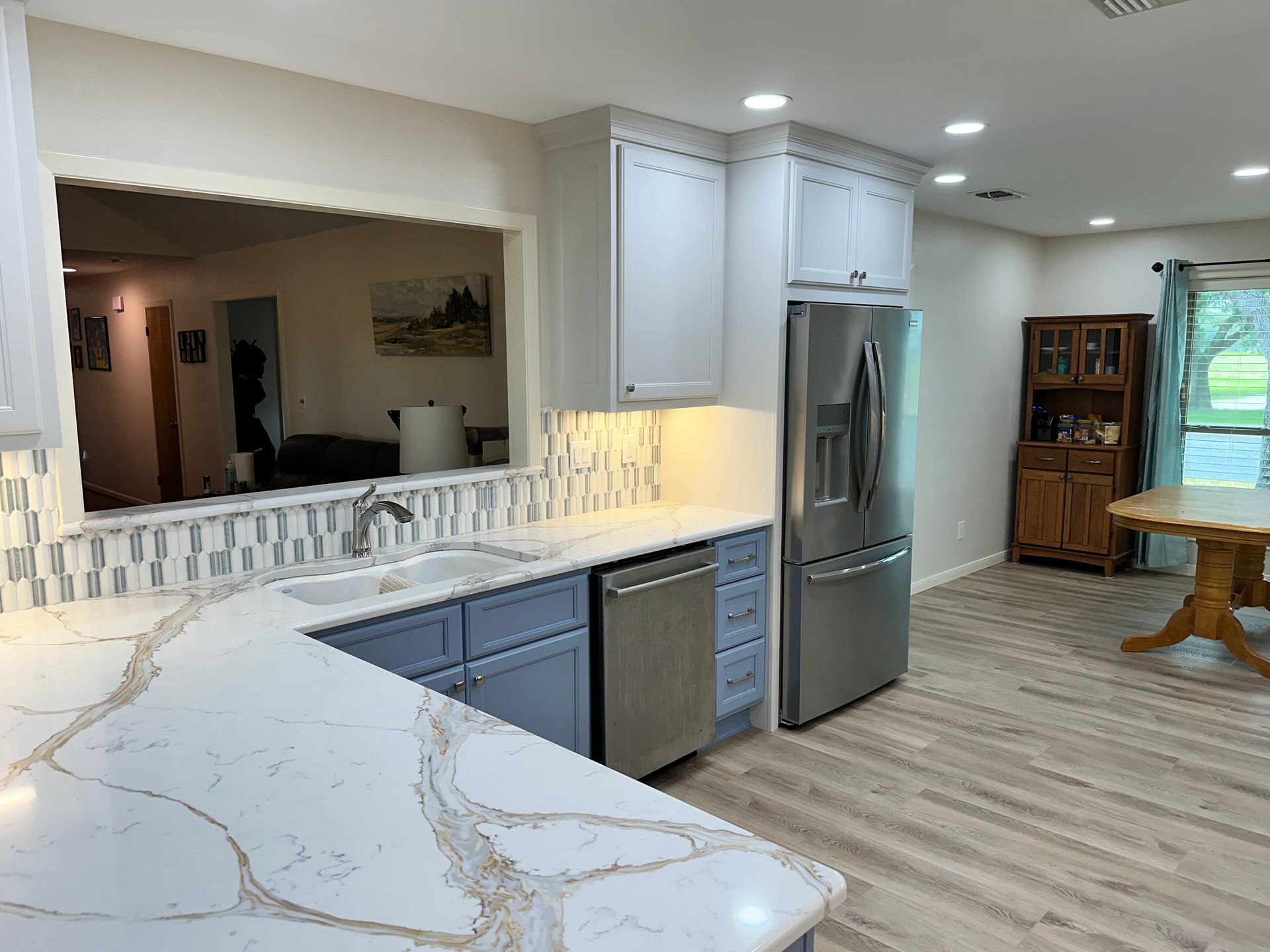 A kitchen with blue cabinets , white counter tops , stainless steel appliances and a refrigerator.