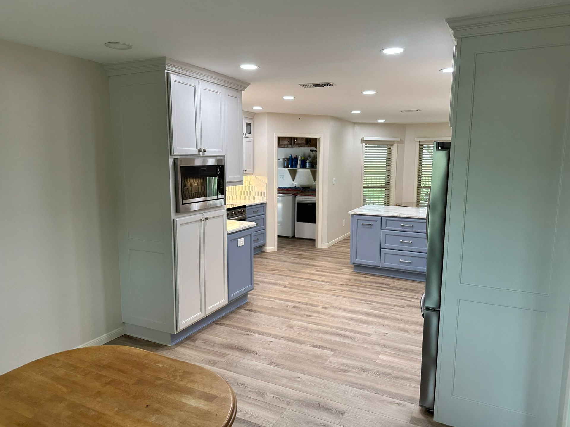 A kitchen with blue and white cabinets and a wooden table.