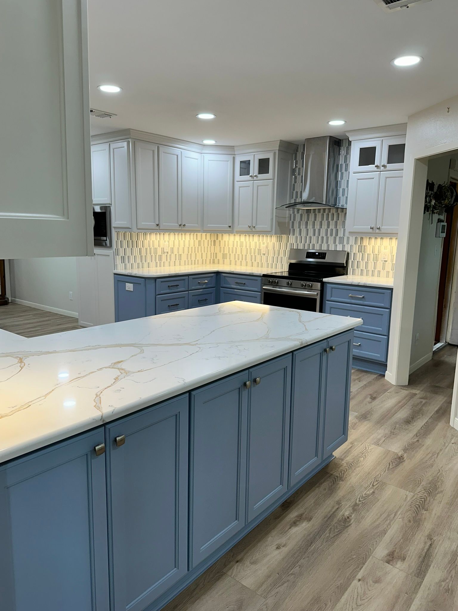 A kitchen with blue cabinets and white counter tops.