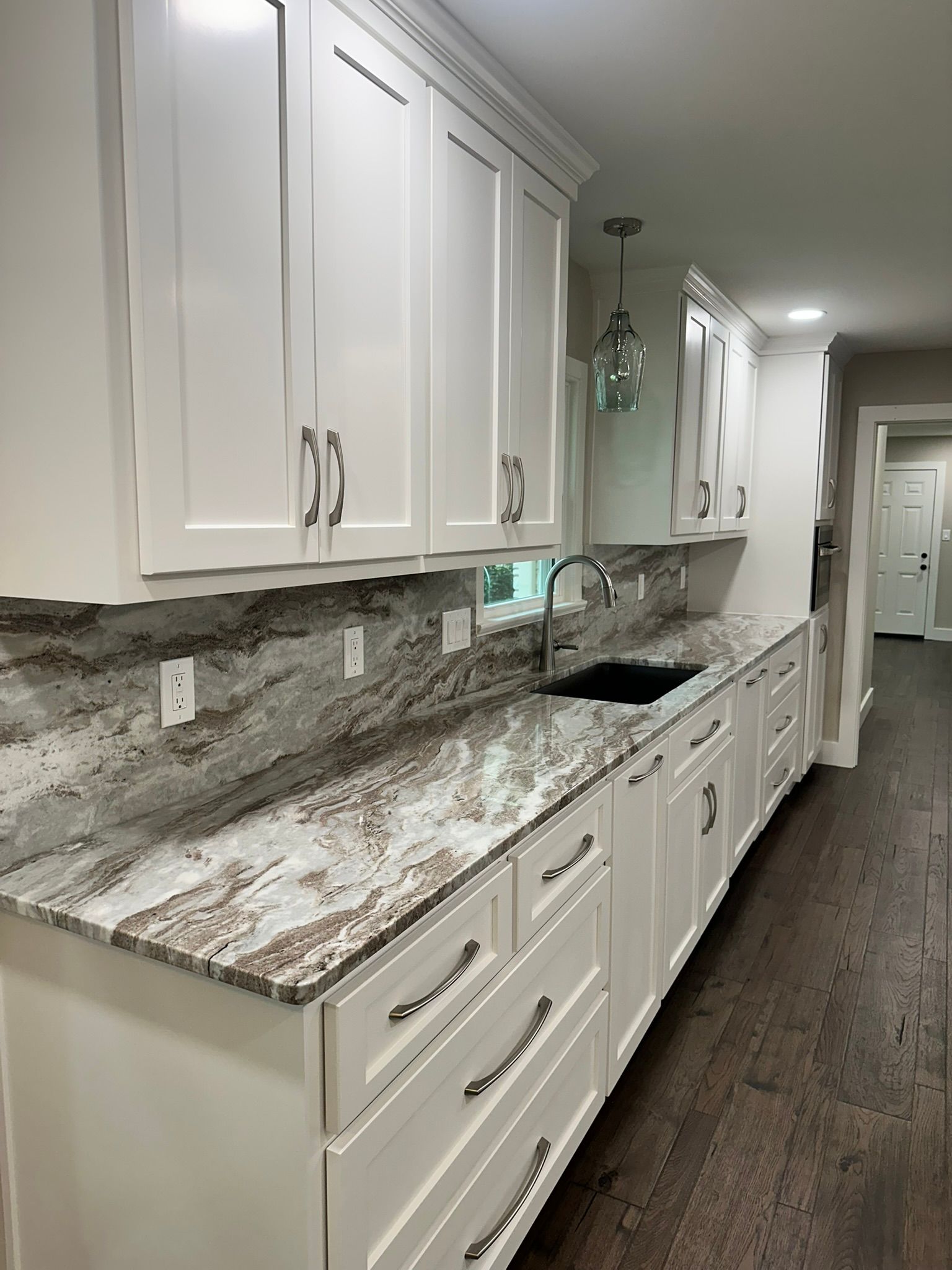 A kitchen with white cabinets and granite counter tops.